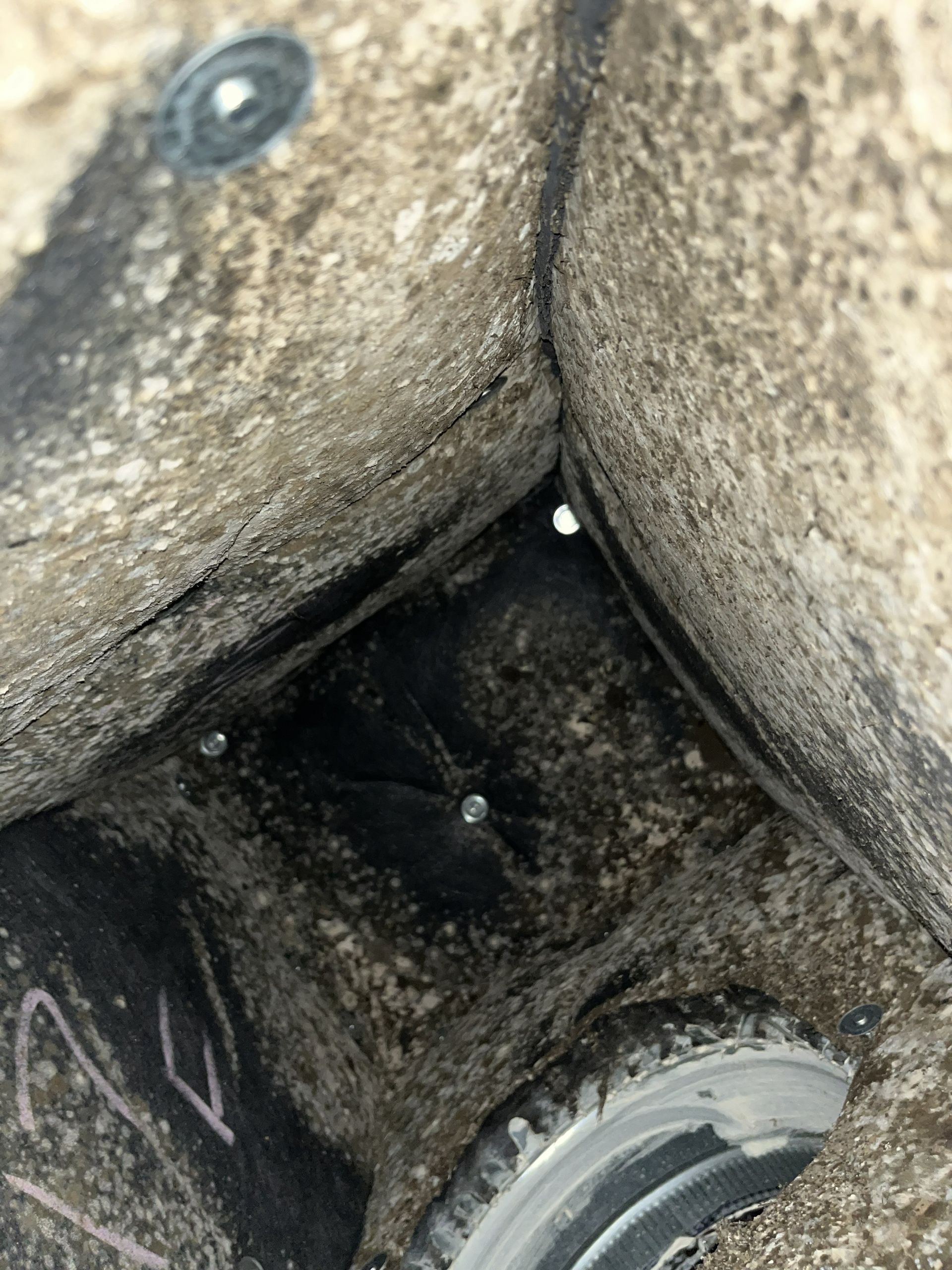 Dirty inside of a container with dark grime and a circular metal opening at the bottom