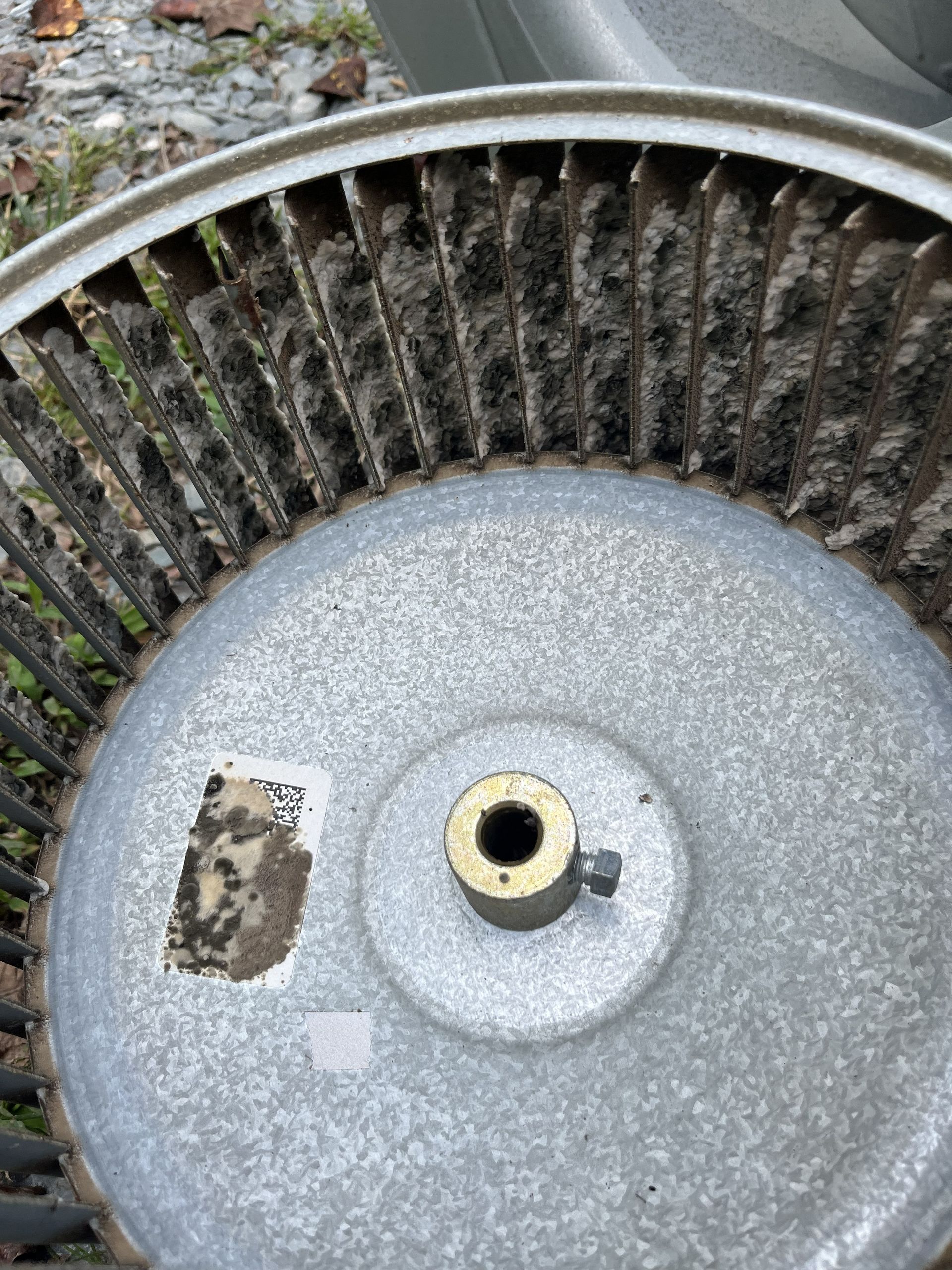 Close-up of a metal industrial fan blade hub with dust and debris around it