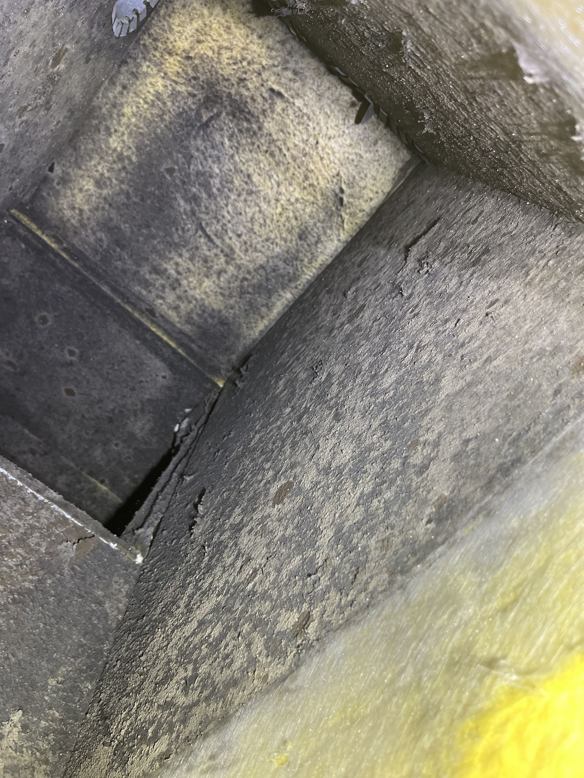 Close-up of gray stone steps and wall with a yellow-painted surface at the bottom right