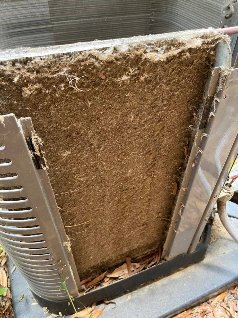 Dirty HVAC condenser coil covered with dust and debris, showing heavy buildup.