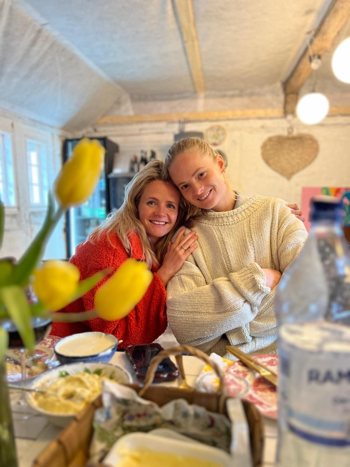 Two women are posing for a picture while sitting at a table.