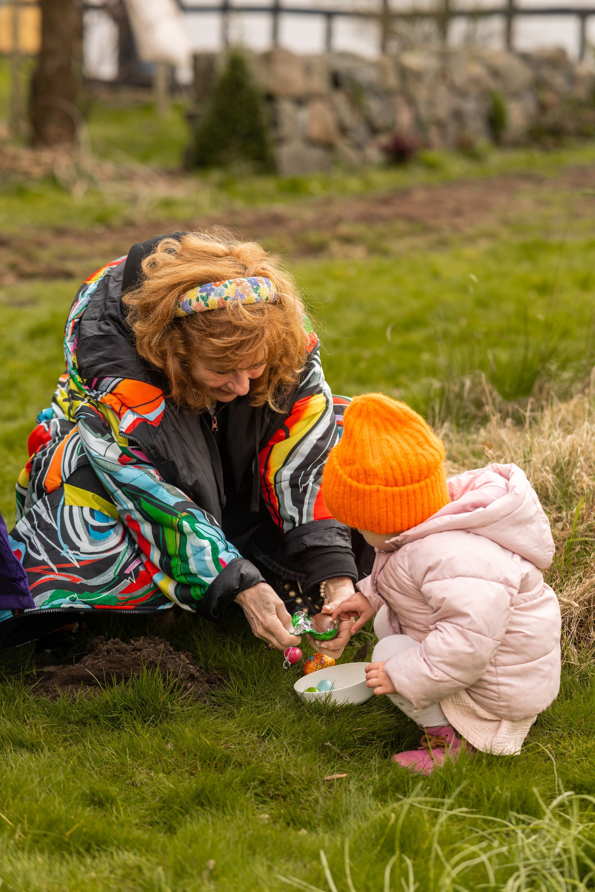 A woman and a little girl are playing in the grass.