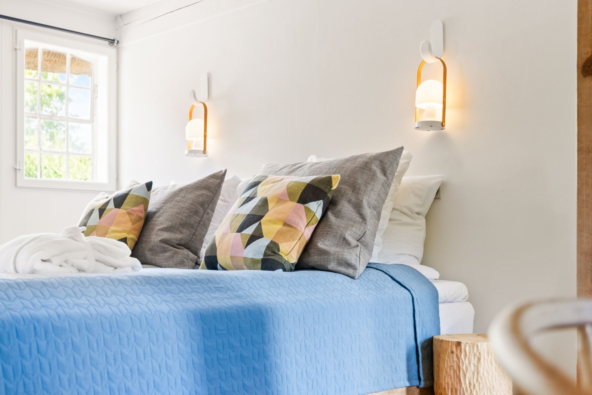 A bed with a blue blanket and pillows in a bedroom.