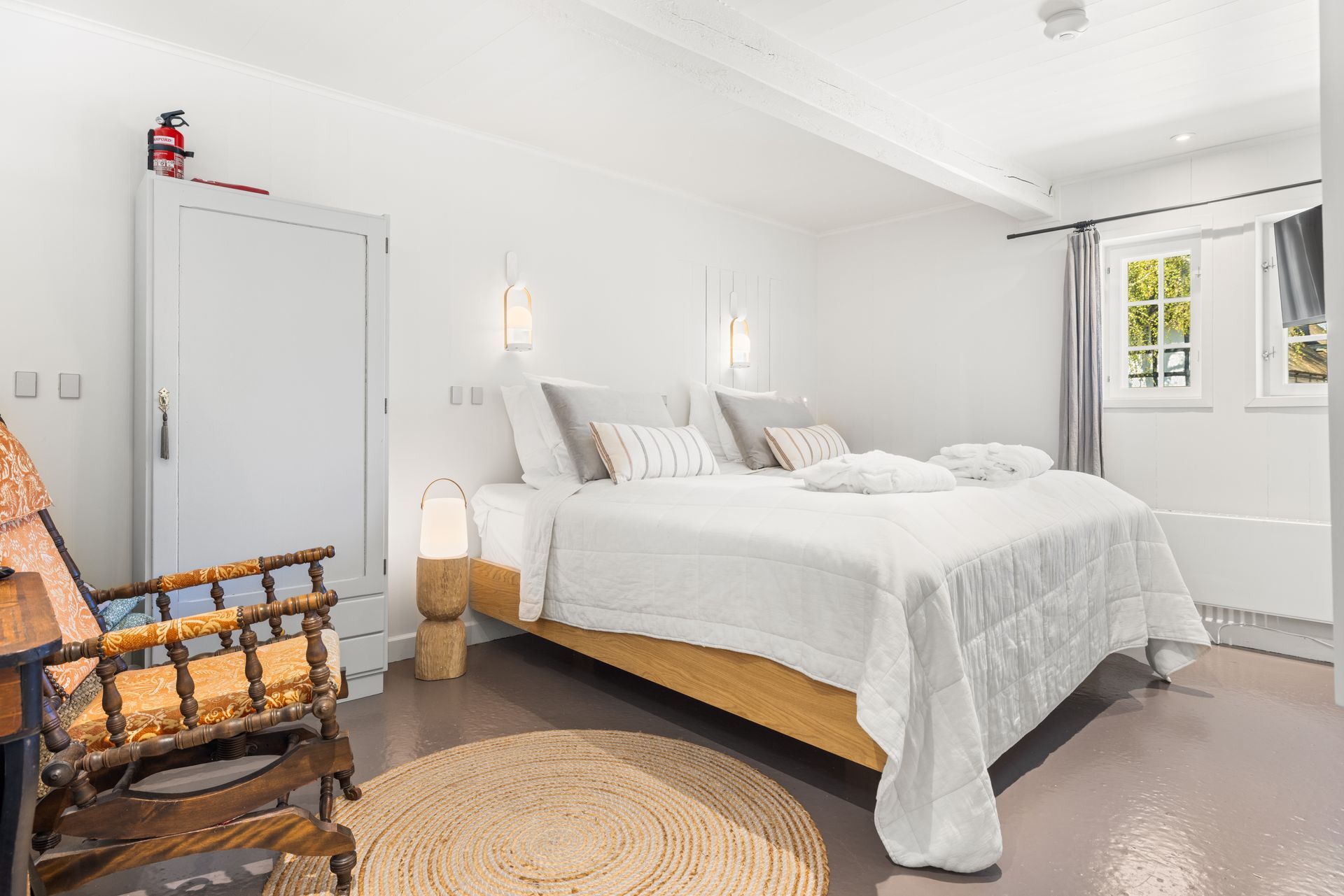 A bedroom with a large bed , a chair , and a rug.
