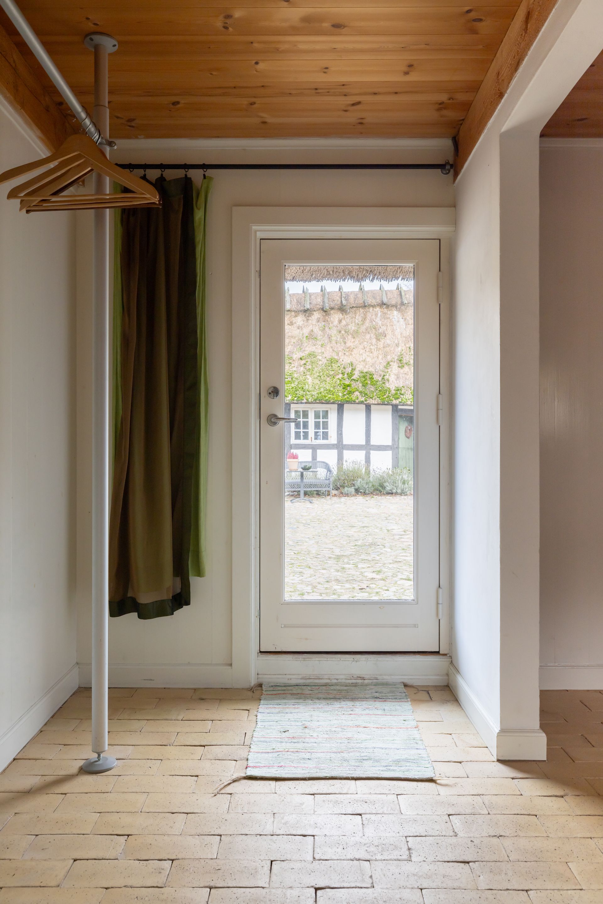 A hallway with a door that is open and a rug on the floor.