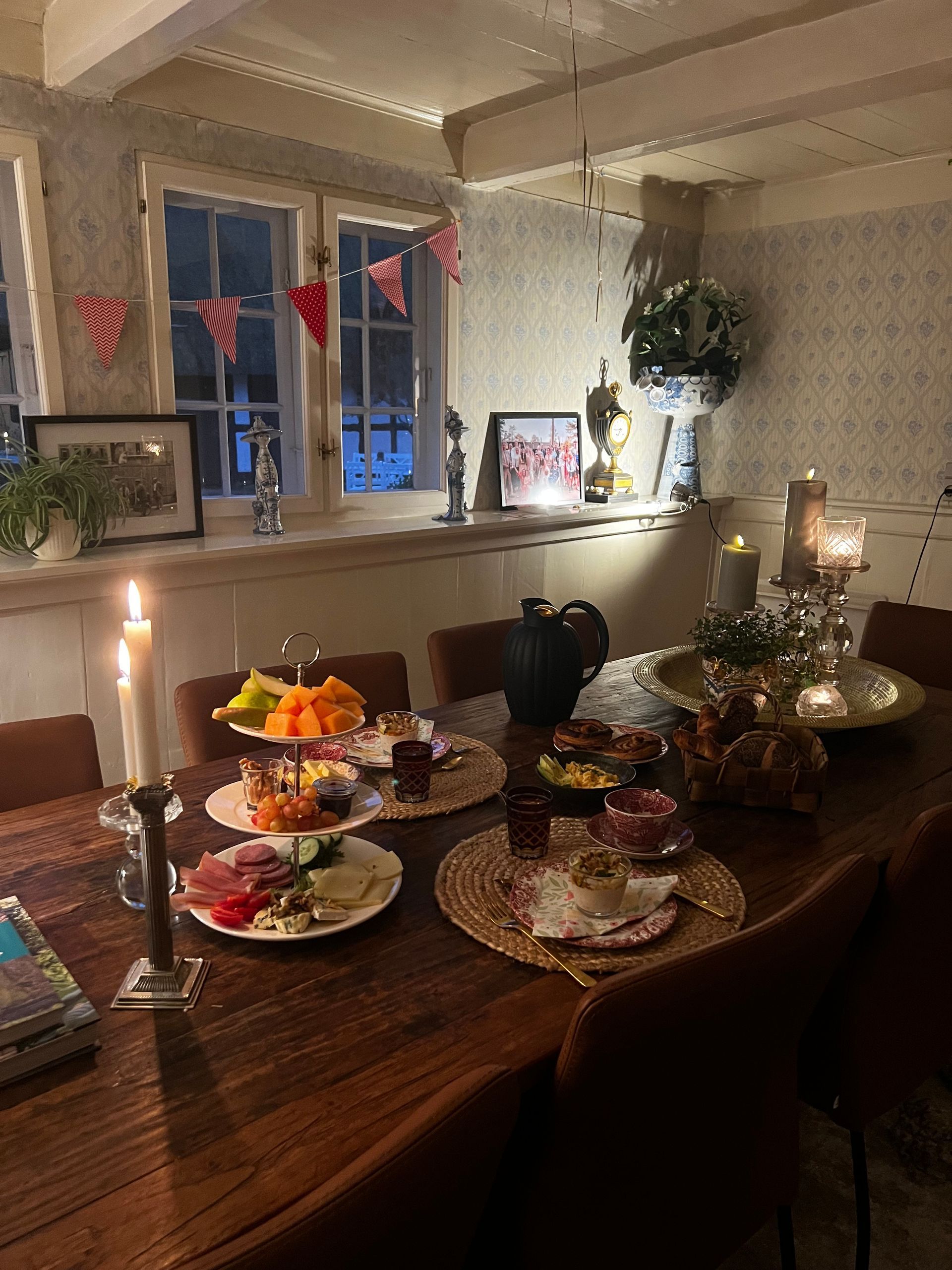 A wooden table with plates of food and candles on it.