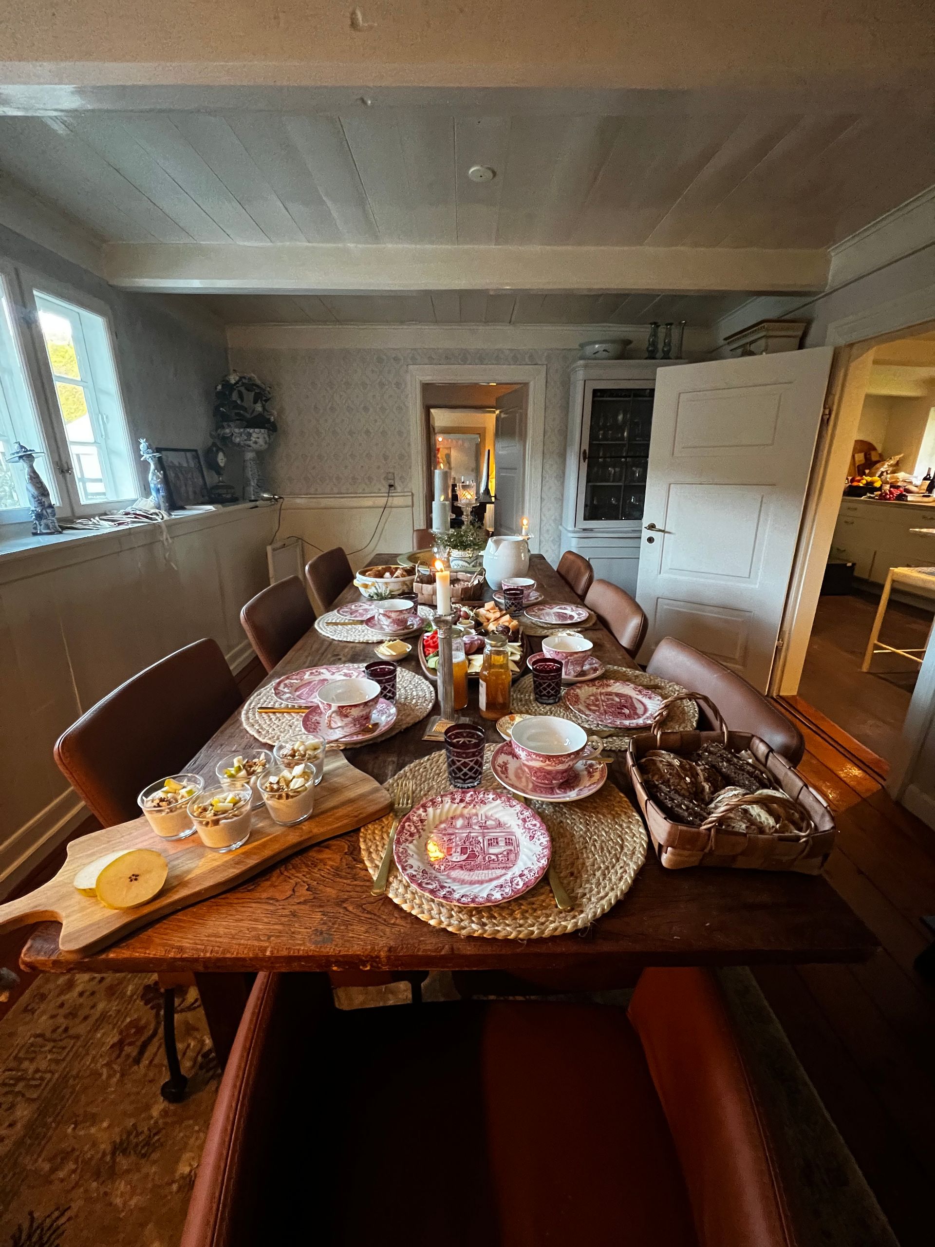 A long dining room table with plates and cups on it.