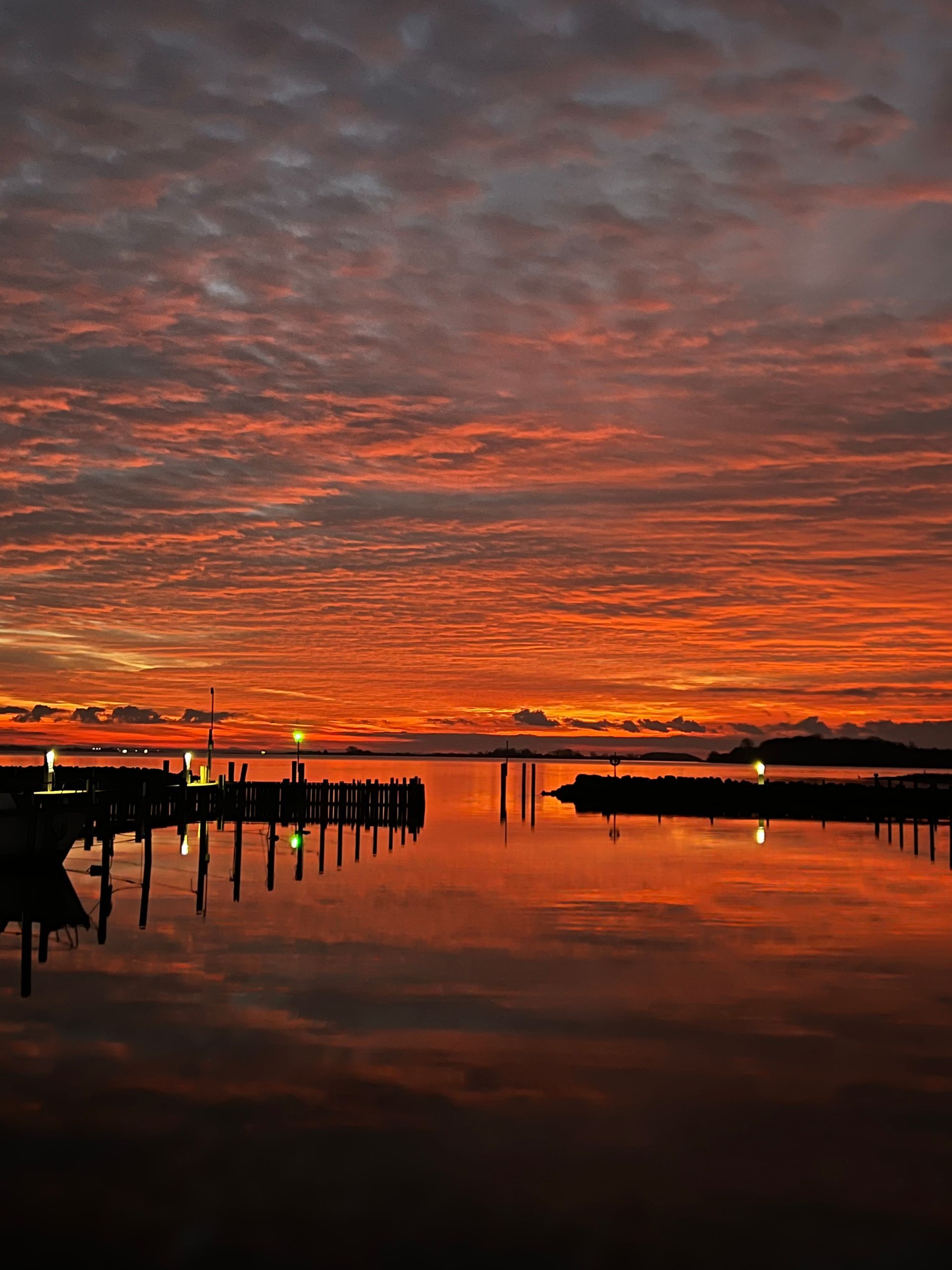 A sunset over a body of water with a dock in the foreground