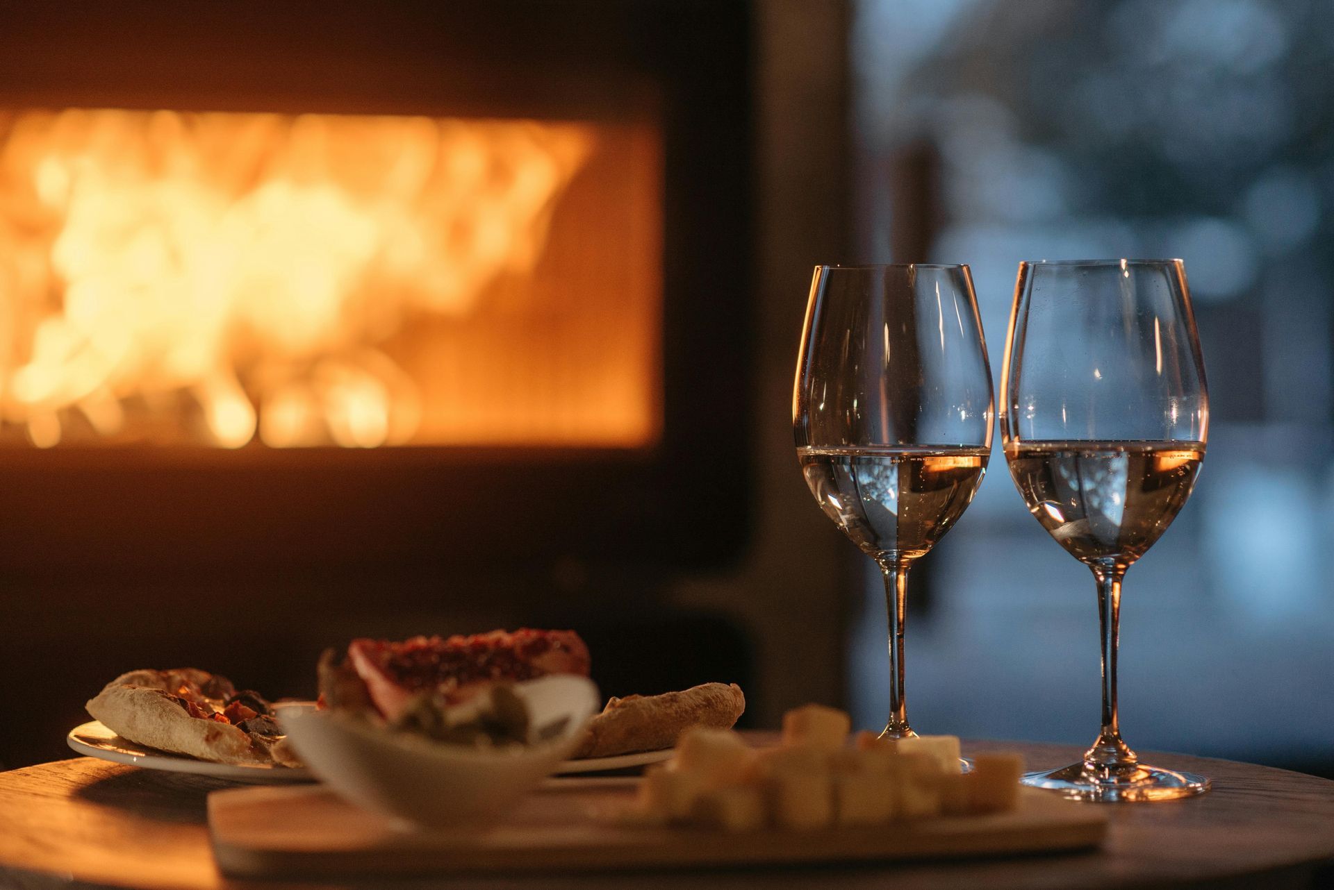 Two glasses of wine and nice snacks by the fireplace at Solbjerggaard—luxurious, cosy moments in the Danish countryside.