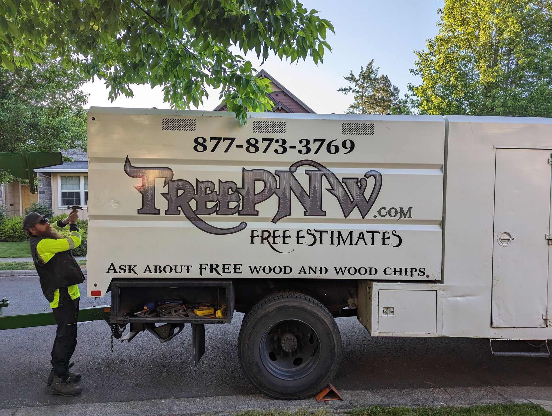 TreeDawg tree service truck with worker beside it in a residential yard