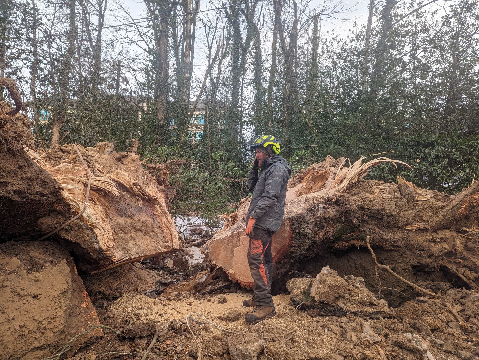 Person in helmet stands between large dirt piles at an outdoor excavation site.