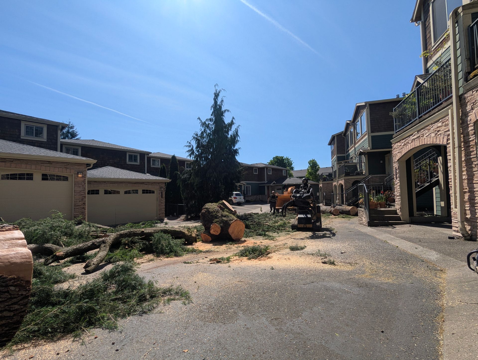 Sunlit construction site between apartment buildings, with debris, equipment, and a partially cleared lot.