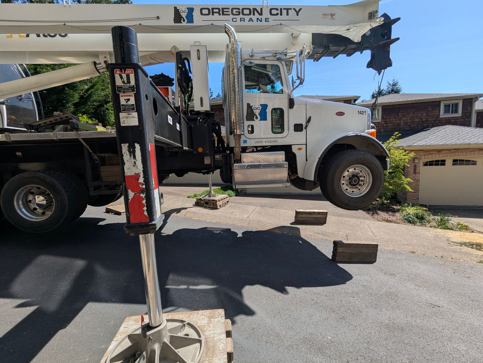 Utility truck with bucket lift extended over a residential street near a house drive.