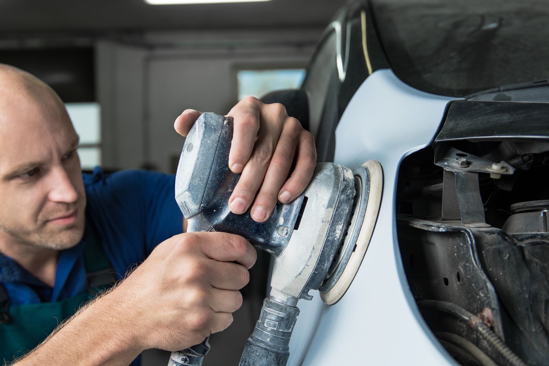 Grinder in the hands of a man who sharpens a car's varnish in the car shop. Grinder in the hands of a man who sharpens a car's varnish in the car shop.