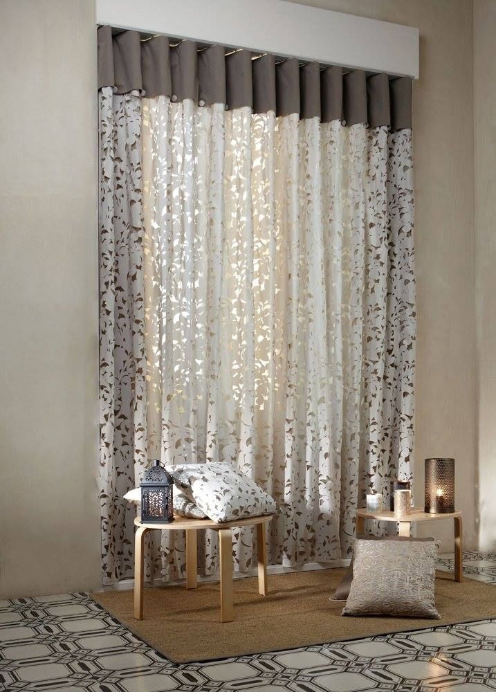 Elegante soggiorno con tende decorate, tavolini e un tappeto intrecciato in tonalità neutre.