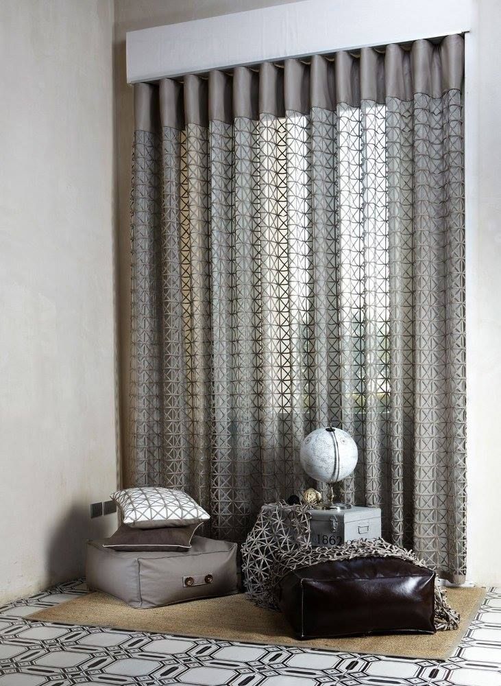 Angolo del soggiorno con tende decorate, cuscini da pavimento e sgabelli decorativi.