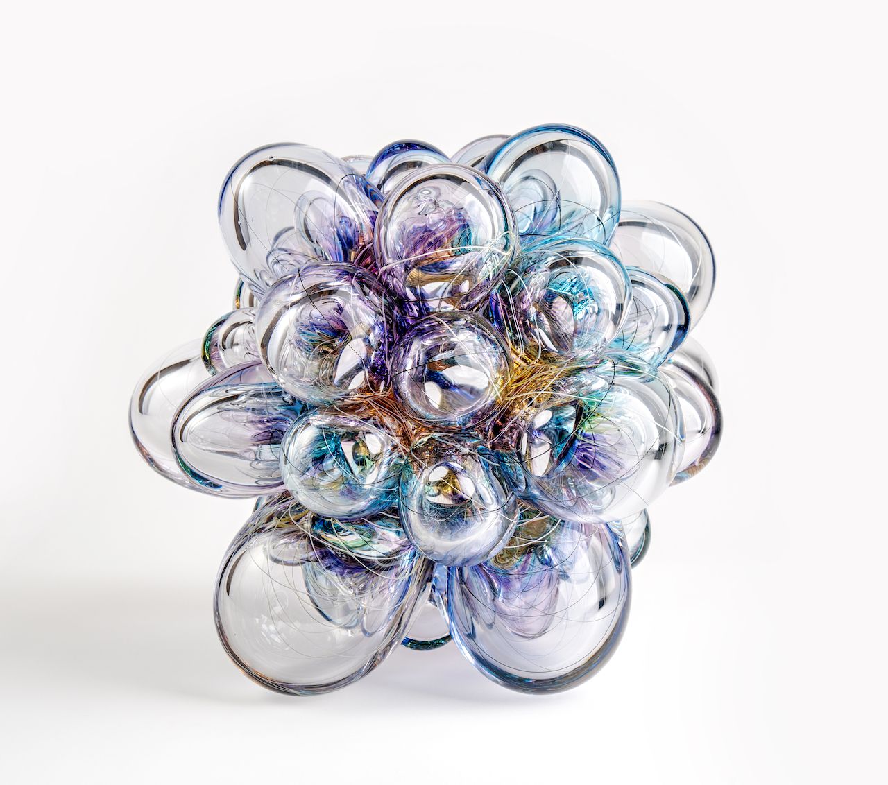 Transparent glass sculpture with iridescent hues, clustered spheres on a white background.