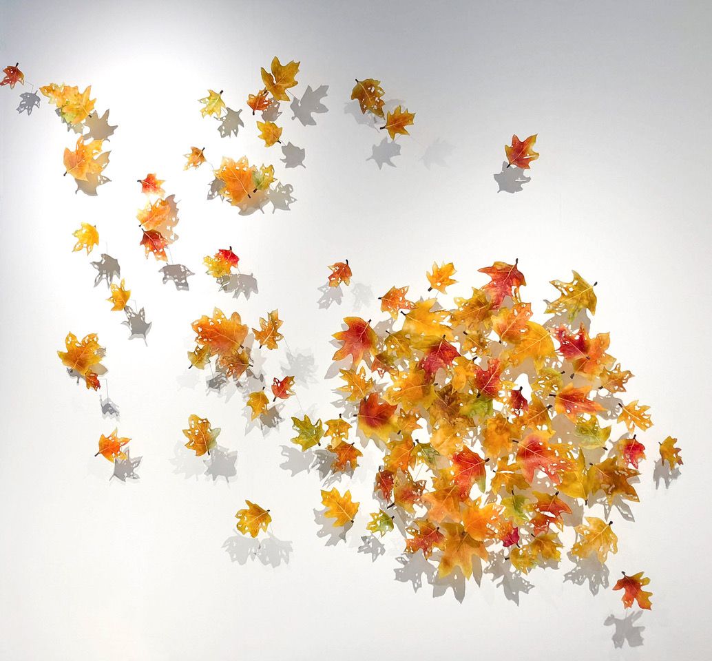 Wall art with orange and yellow leaf arrangement, creating the illusion of falling foliage.