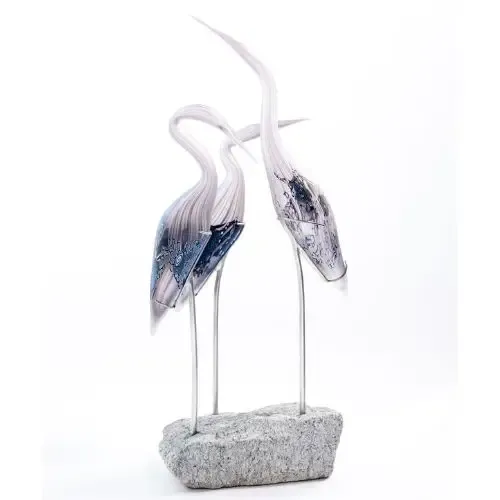 Two glass heron sculptures on a stone base; silver and blue tones.