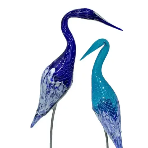 Two glass bird sculptures: one blue, one turquoise, with long necks and metal legs.