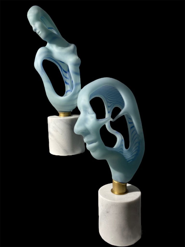 Two blue abstract sculptures on white marble bases, one a face, the other a figure, on a black background.