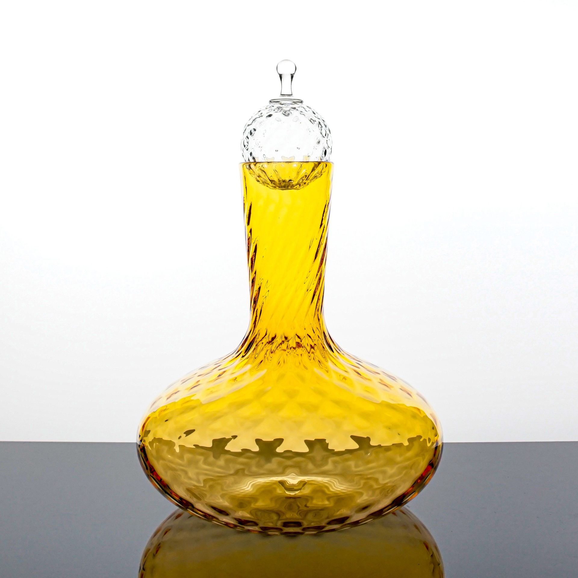 Yellow glass decanter with a textured body, holding yellow liquid, topped with a glass stopper.