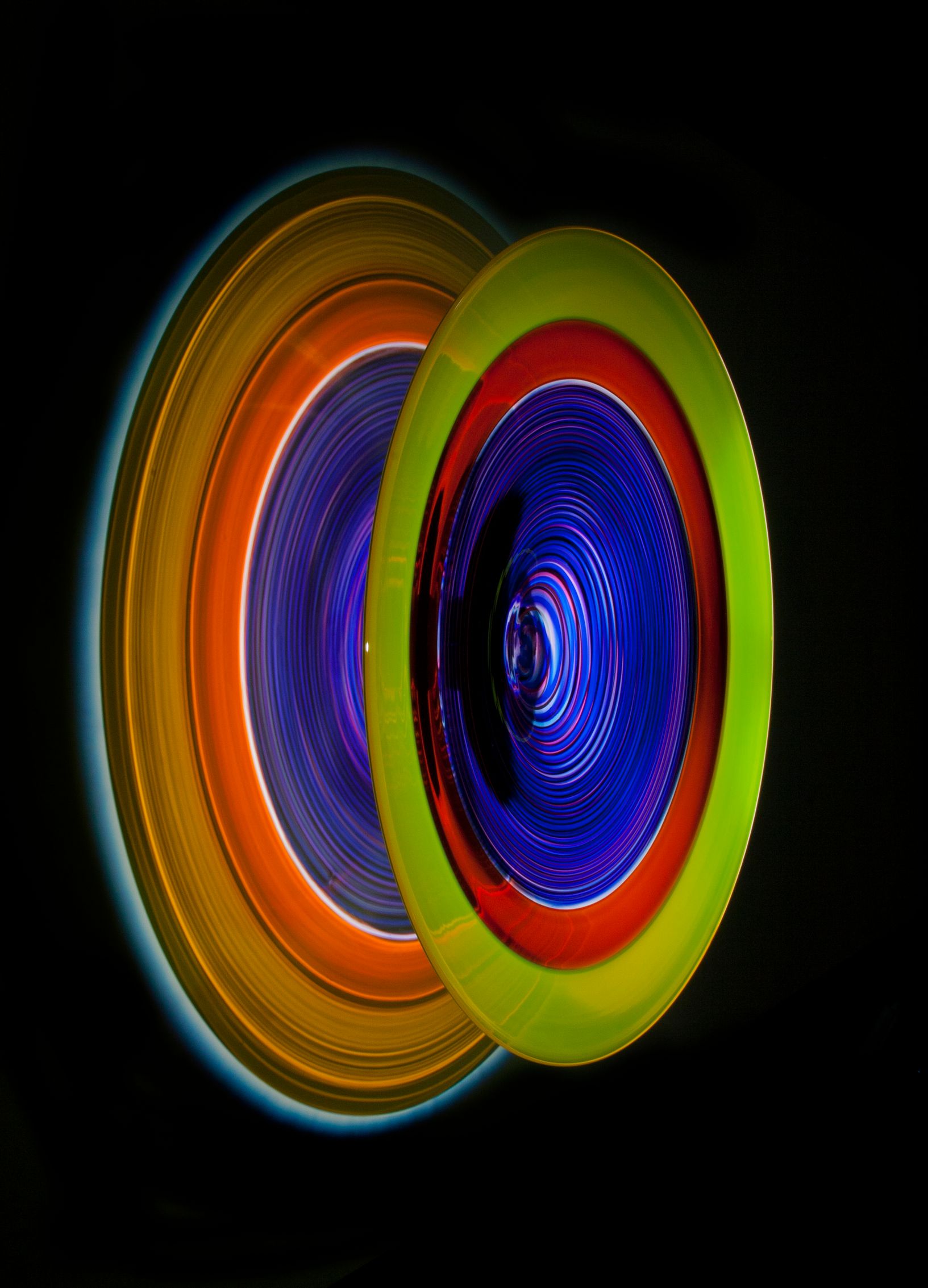 Abstract rings of color, mostly orange, yellow, red, and blue, against a black background.