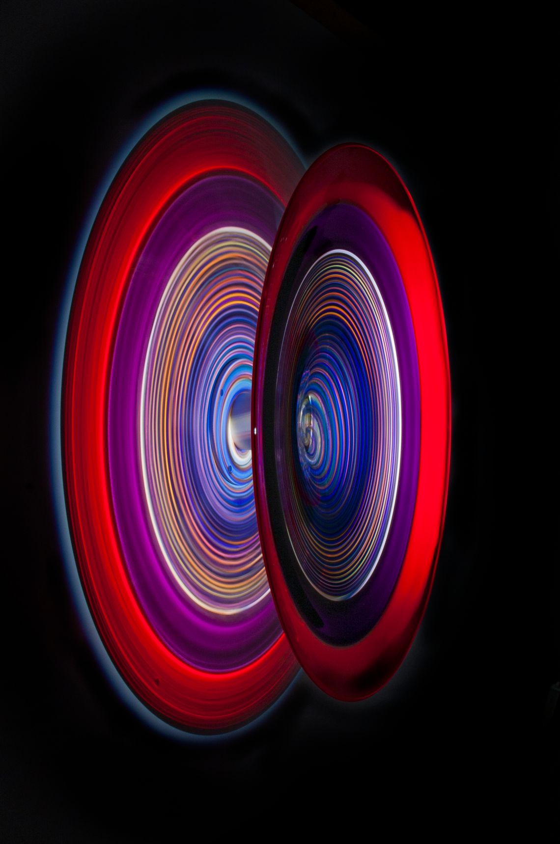 Concentric rings of red, purple, and blue light against a black background.