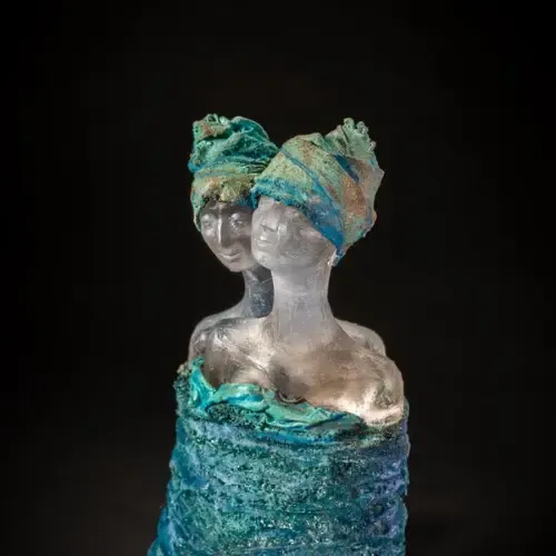 Sculpture of two women, one behind the other. Teal and blue colors. Heads wrapped in fabric.