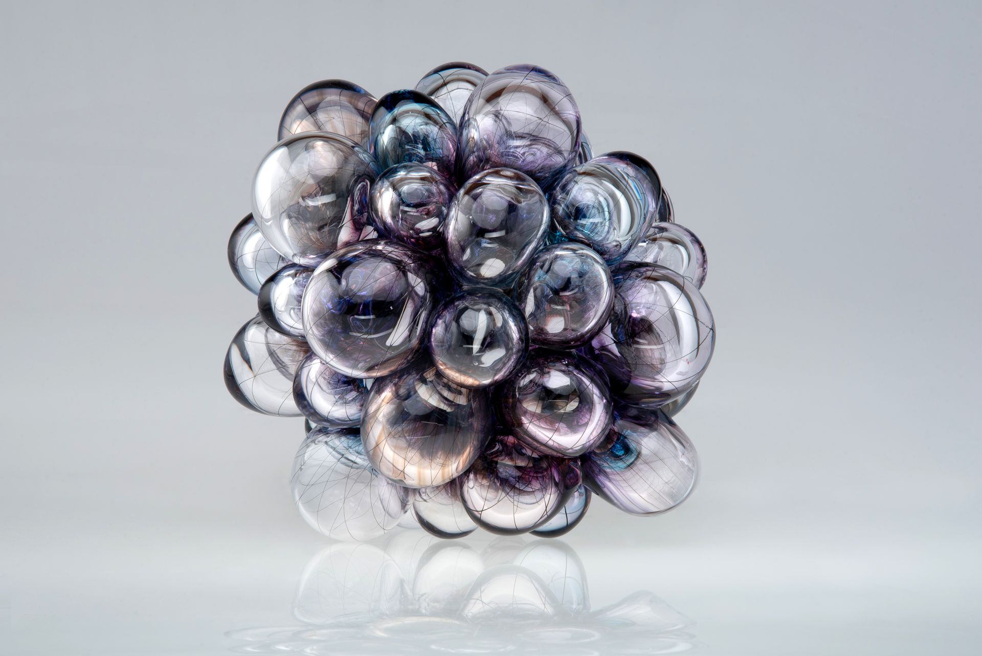 Cluster of iridescent glass bubbles in shades of purple, silver, and blue.