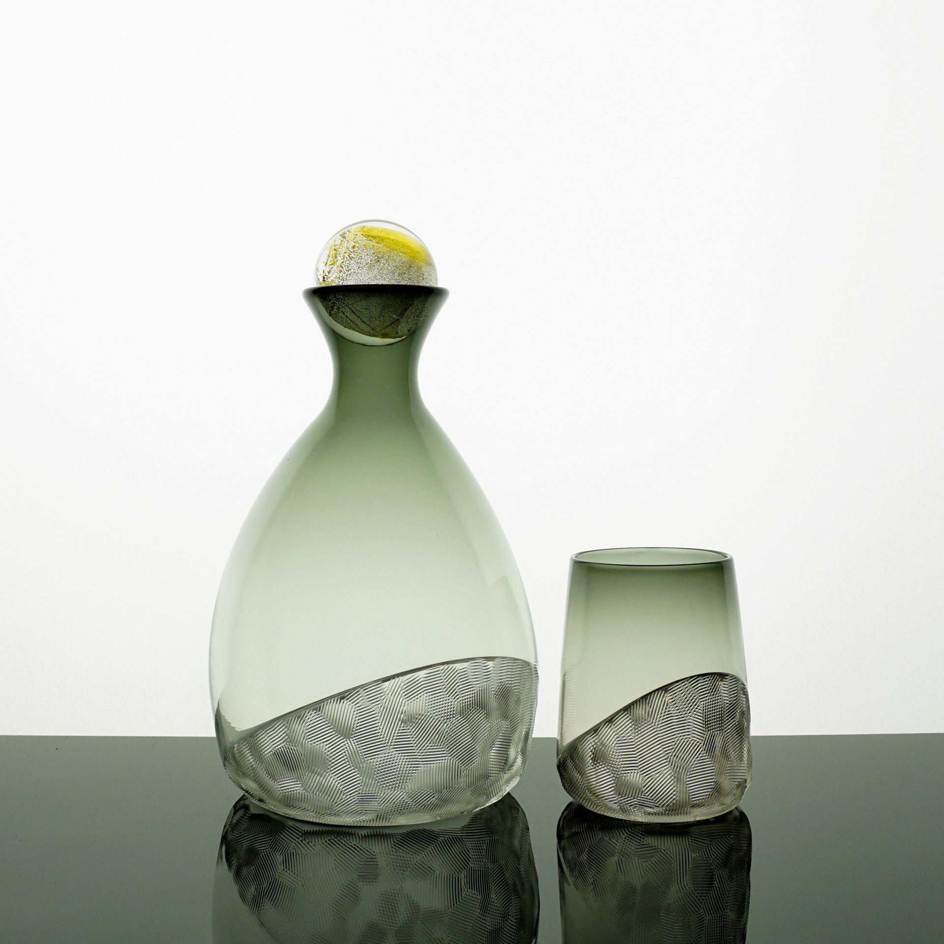 Green glass decanter with a matching tumbler; both have a patterned, textured base.