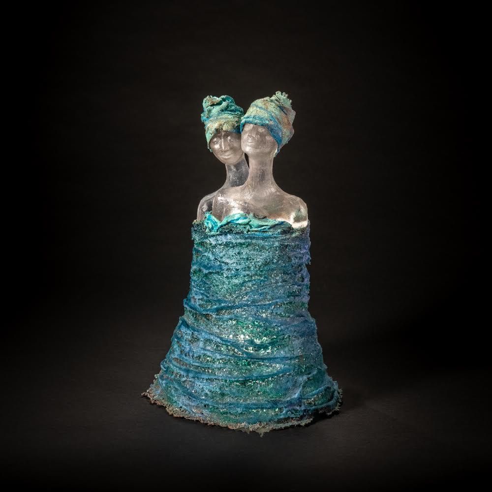 Sculpture of two figures fused at the shoulders, wearing blue head coverings and draped in blue, textured material.