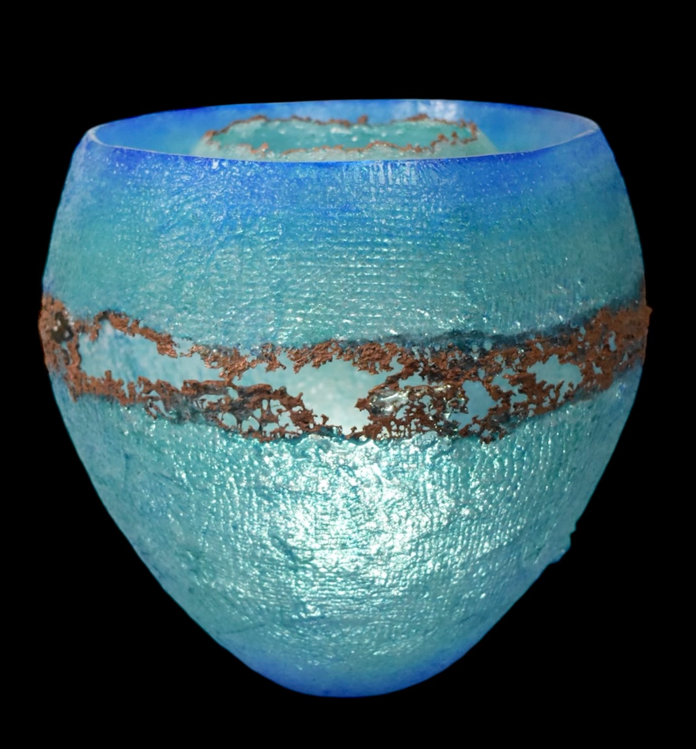 Blue and turquoise glass vase with a textured surface, copper band around the middle, against a black background.