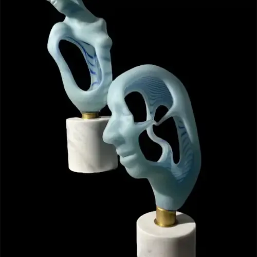 Two light blue sculptures on marble bases, one a face profile, the other abstract, against a black background.