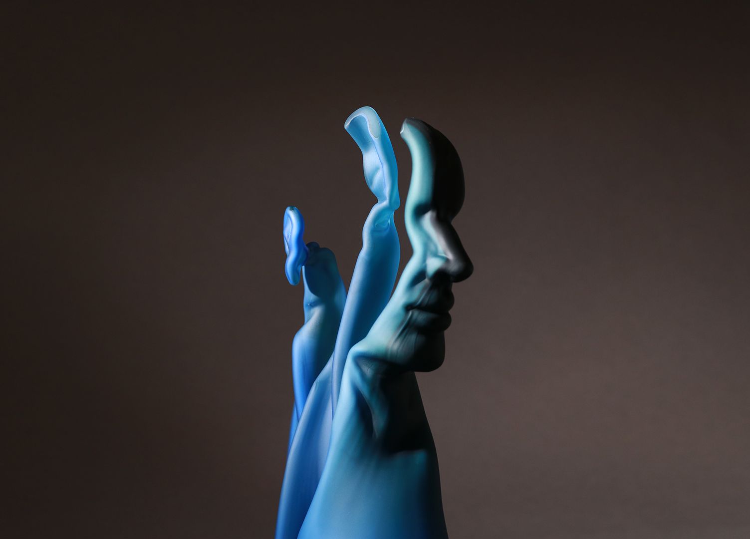 Blue rubber glove shaped as a profile of a human face, dark background.