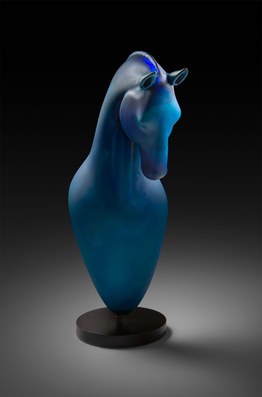 Blue glass horse sculpture on a dark round base.