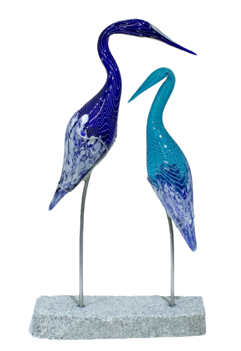 Two glass heron sculptures, blue and turquoise, on metal legs and a stone base.