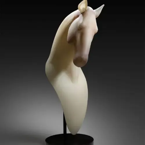 Sculpted glass horse head, cream-colored, with a dark base and setting.