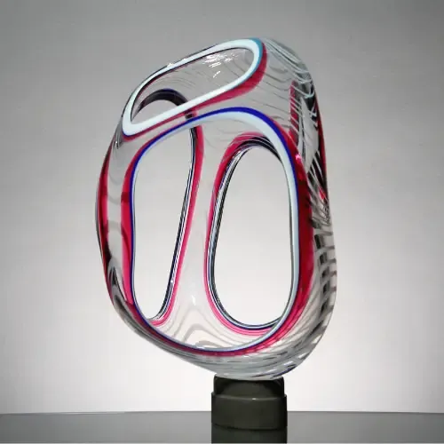 Clear glass sculpture with red, blue, and white swirls, mounted on a dark gray base.