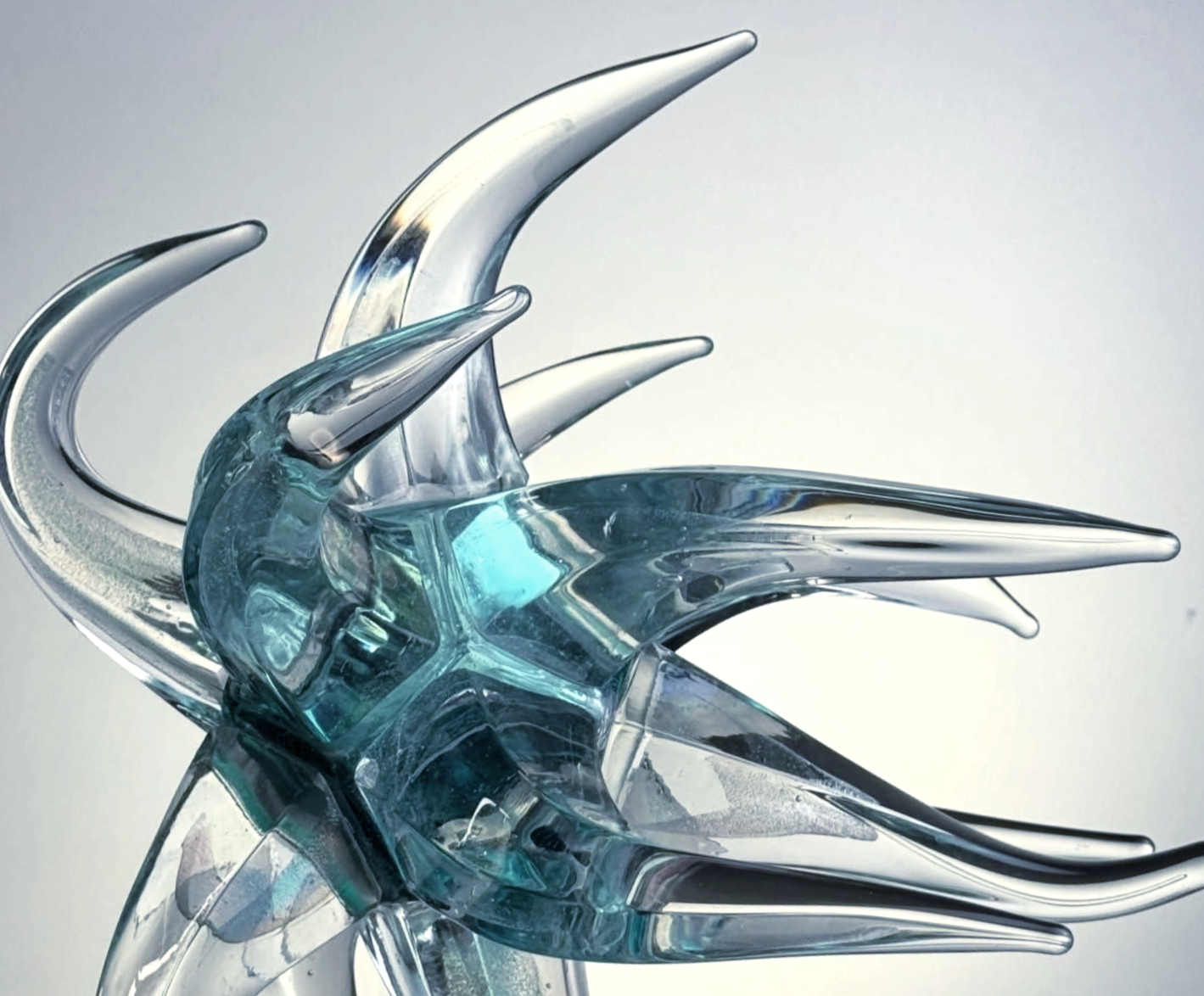Abstract glass sculpture, blue and clear, with pointed, curved shapes.