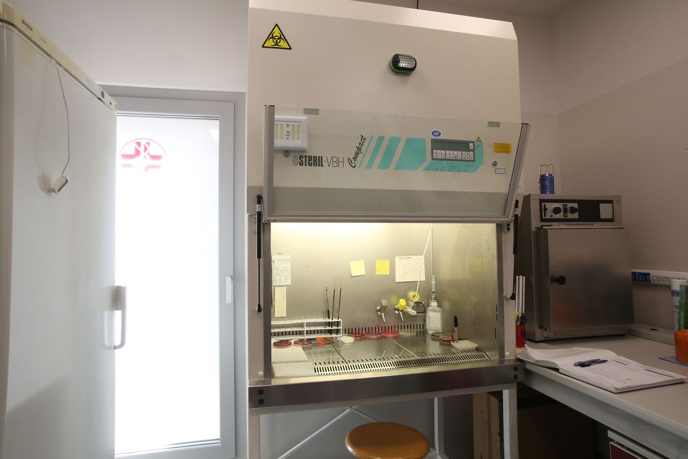 Cabina di biosicurezza da laboratorio con attrezzature, lavello e piano di lavoro in un'area di lavoro pulita.