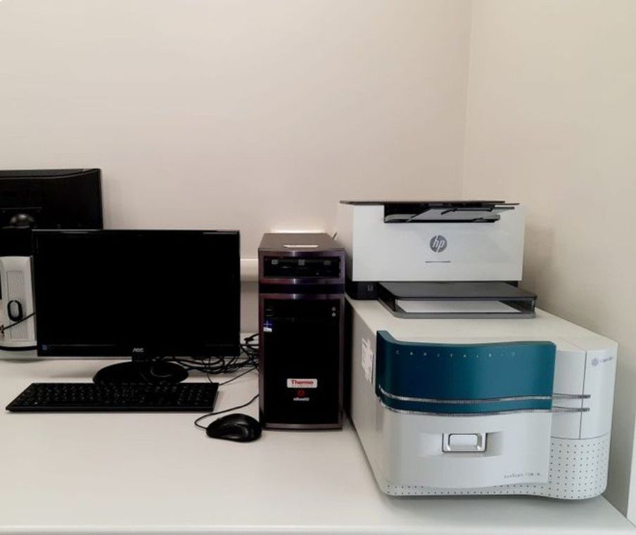 Scrivania da ufficio con monitor, tastiera, case e stampanti/scanner impilati su un tavolo bianco.