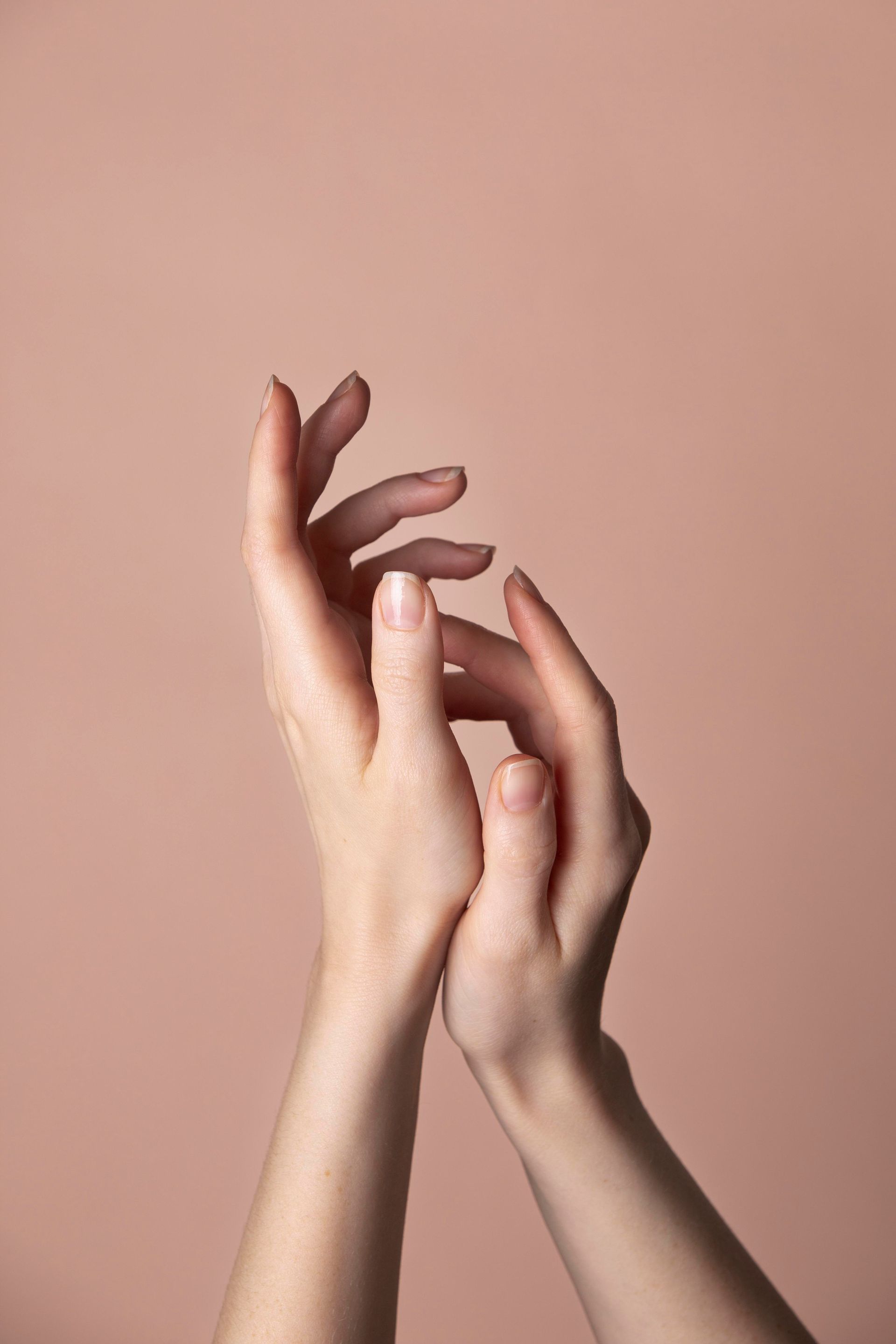 Un gros plan des mains d'une femme sur un fond rose.