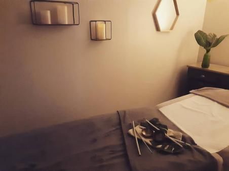 Une table de massage dans une pièce avec des bougies au mur.