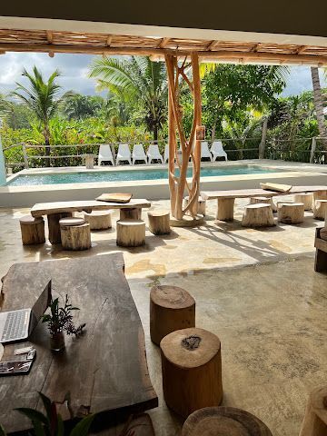 Outdoor seating area with pool, tree trunk stools and tables, and tropical foliage.