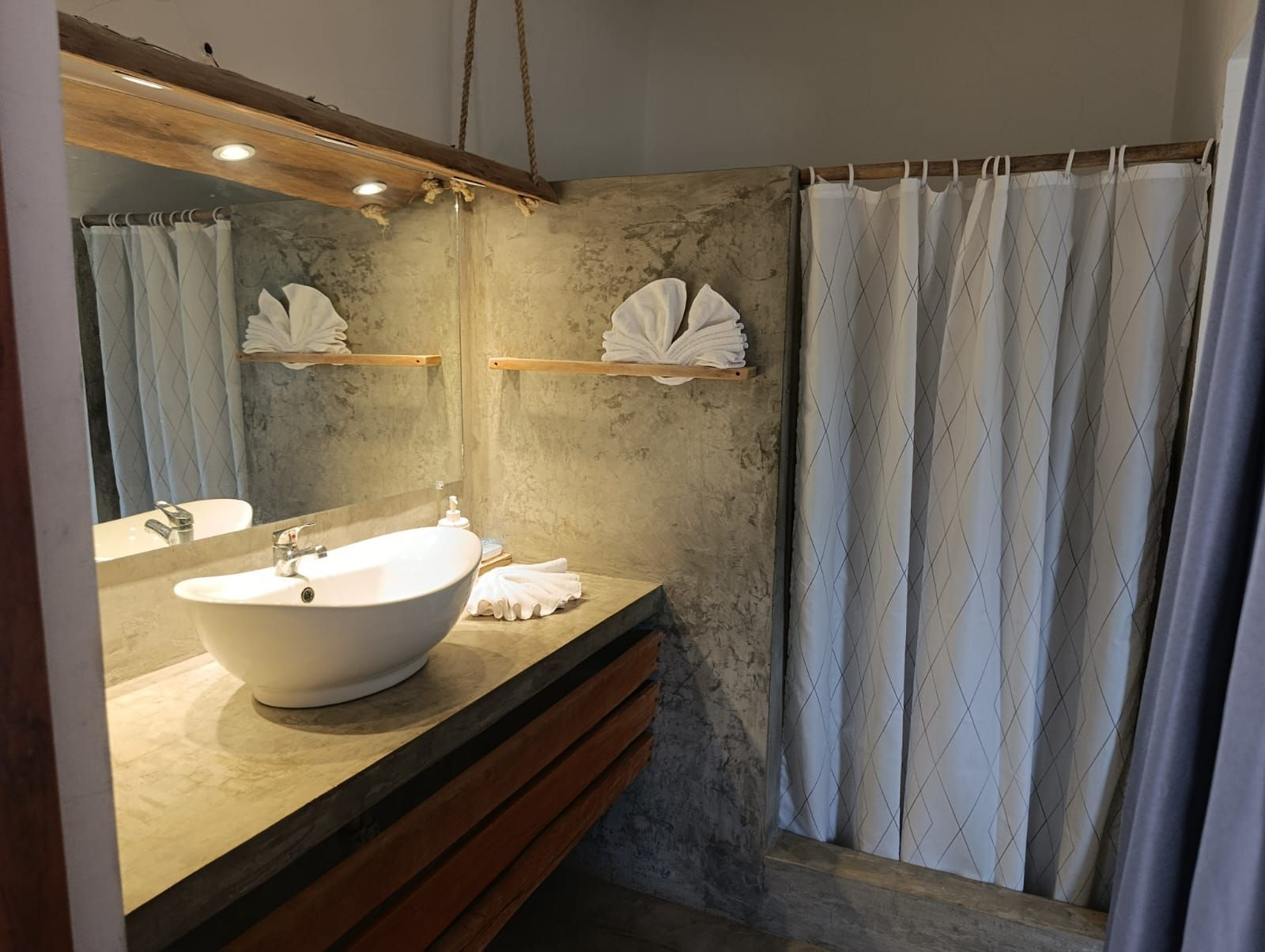 Bathroom with concrete walls, a white sink, mirror, and shower curtain.