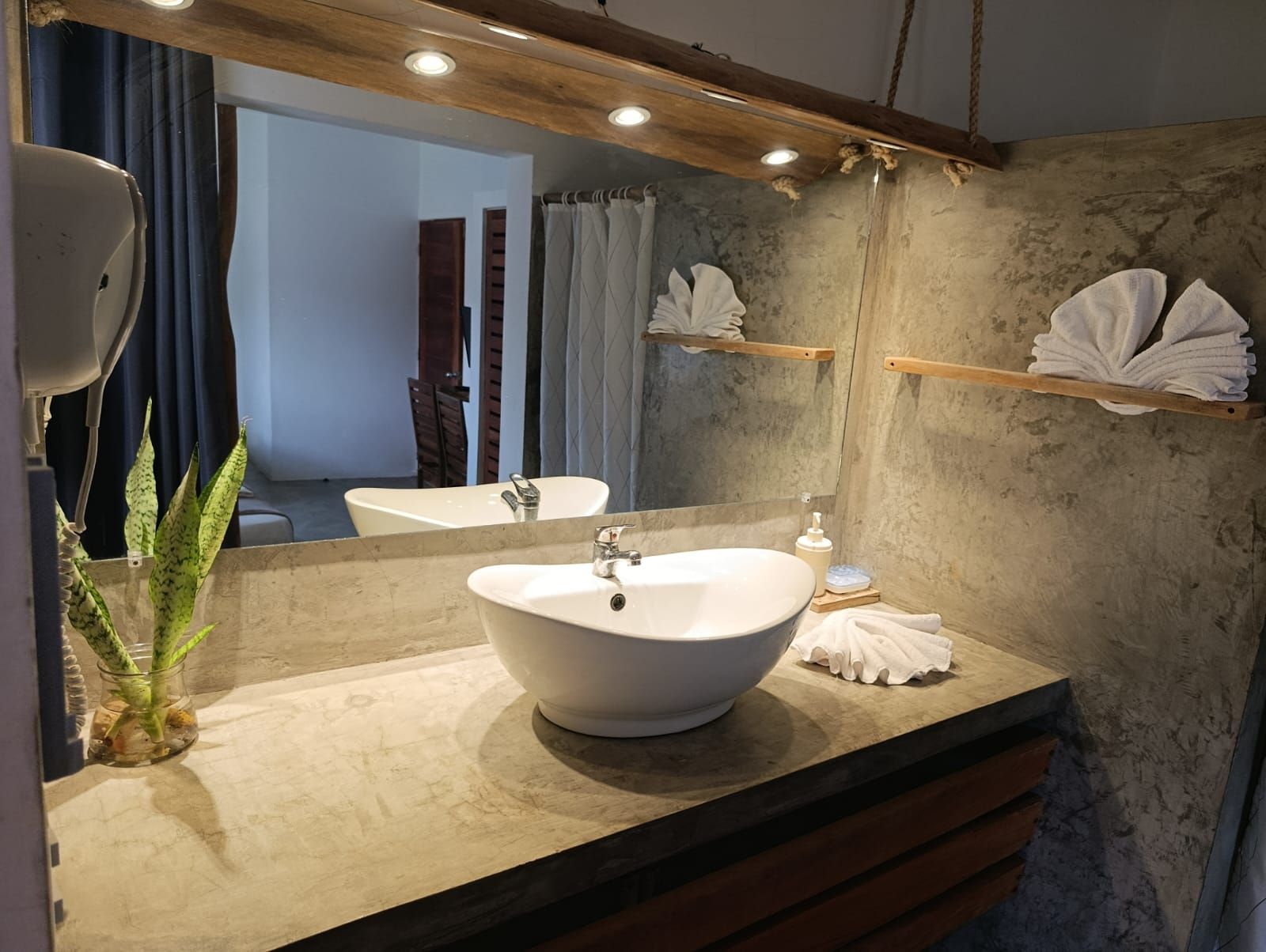 Bathroom with concrete countertop, white vessel sink, large mirror, and rustic wood accents.