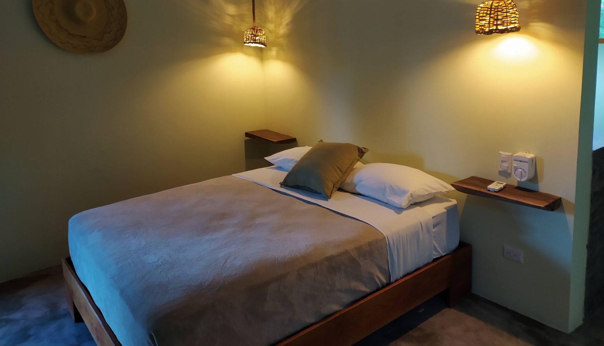 Bedroom with a bed, two lamps, and a small nightstand. Warm lighting.