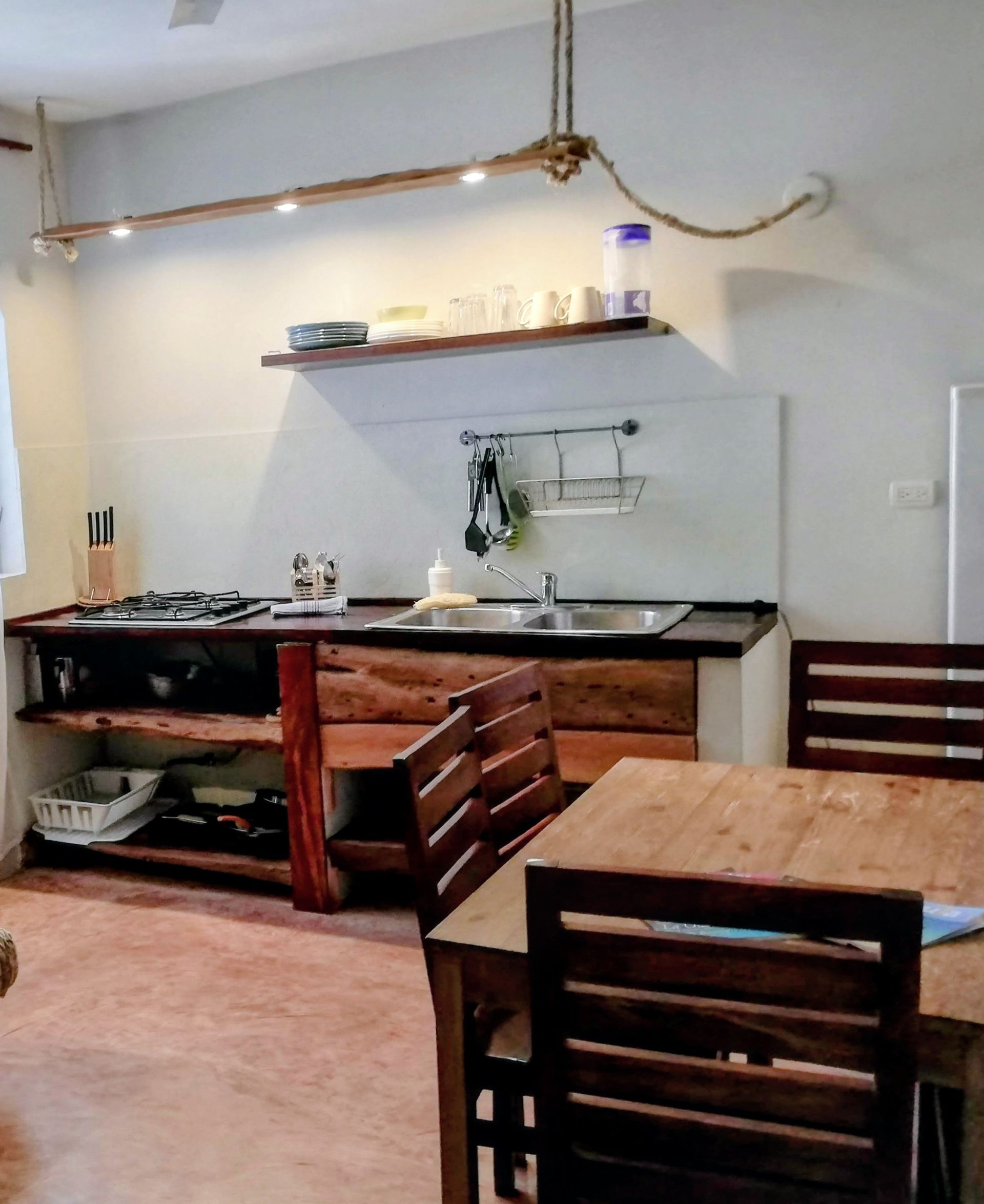 Rustic kitchen with wood cabinets and dining table; overhead rope lighting.