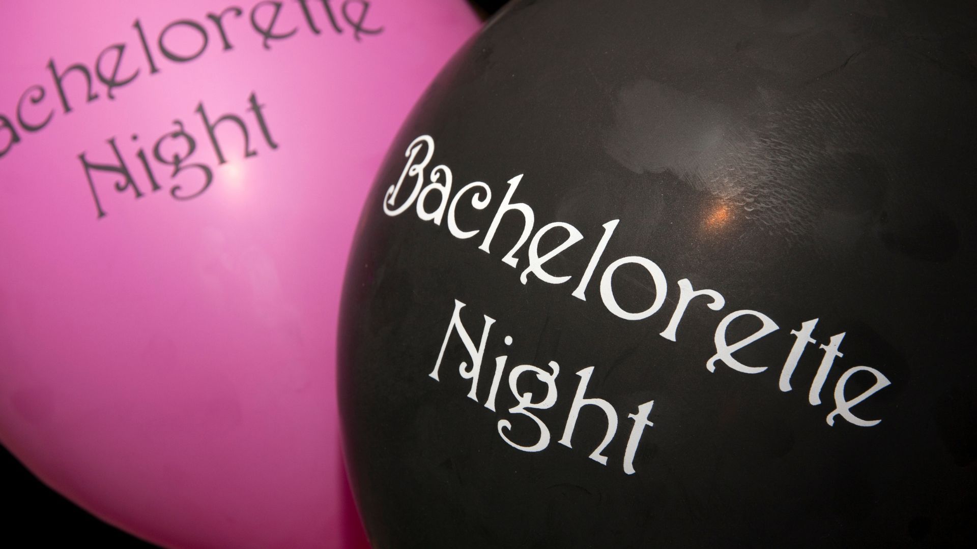 A pink bachelorette night balloon sits next to a black bachelorette night balloon